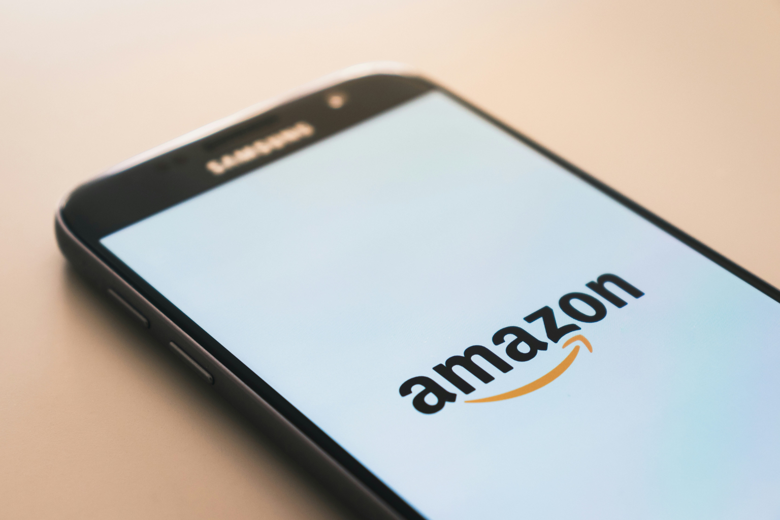 A smartphone displaying the Amazon logo on its screen against a light background hints at an in-depth journey through the Amazon ecosystem. The sleek design of the phone, with the logo prominently centered, invites you to explore a comprehensive guide on Amazon Inspect Returns.